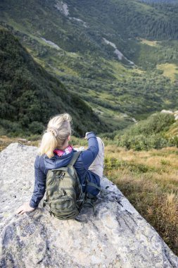 Uzun yürüyüşe çıkan kimse sırt çantası dağın zirvesinde rahatlatıcı ile.