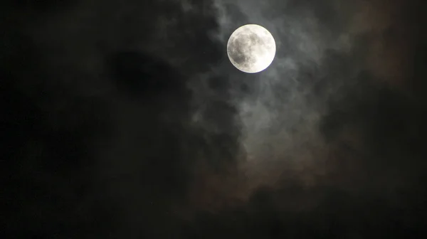 full moon with clouds around in shades of colors
