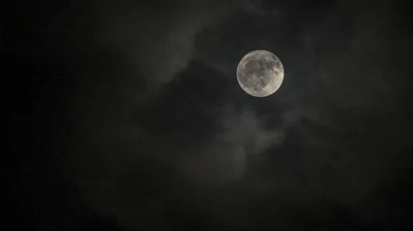 full moon with clouds around in shades of colors