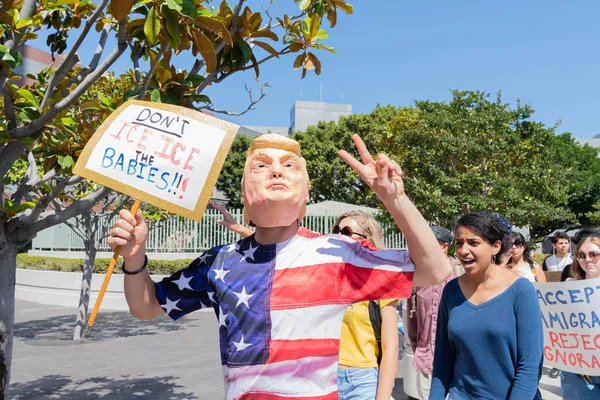 Los Angeles, 30 Haziran 2018: aileler ait birlikte Mart çevresinde Büyükşehir gözaltı merkezi başkanı Donald Trump'ın sıfır tolerans Göçmenlik politikası protesto sırasında Donald Trump maskeli bir aktivist.