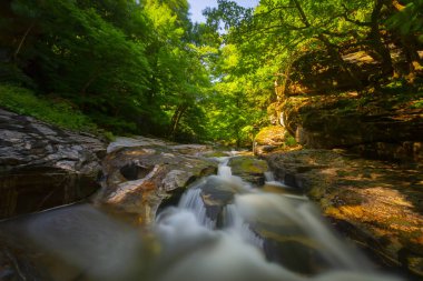 Mustafa Kemal Paşa'da Suuctu şelaleleri, Bursa, Türkiye. Ağaçlar arasında güzel şelale, yeşil yapraklar, kayalar ve nehir arka plan ile gizli ormanda taşlar.