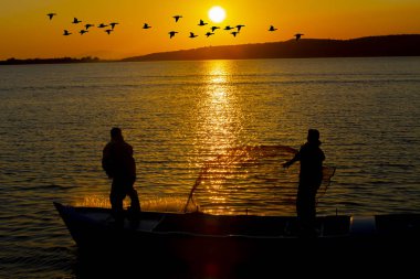 Gün batımı sahilde siluet balıkçı balıkçılık net; sinematik steadicam çekim