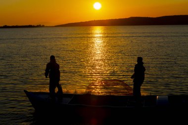 Gün batımı sahilde siluet balıkçı balıkçılık net; sinematik steadicam çekim