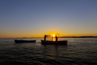 Gün batımı sahilde siluet balıkçı balıkçılık net; sinematik steadicam çekim