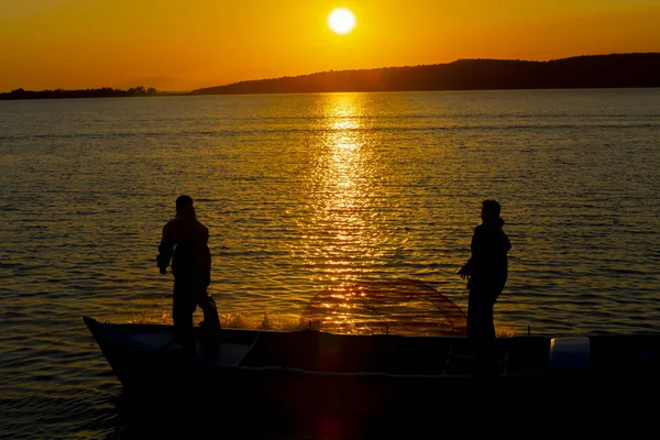 Gün batımı sahilde siluet balıkçı balıkçılık net; sinematik steadicam çekim