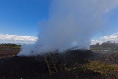  Çok az oksijen ile yavaş yanan odun yığını üzerinde iş başında bir kömür üreticisi.