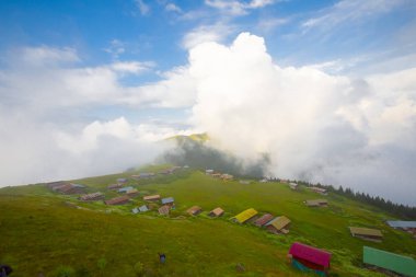 Türkiye'nin kuzeydoğusundaki Karadeniz bölgesinin yeşil doğası, karlı dağları ve geleneksel ahşap yayla evleri (yayla evi). Haziran 2019'da Rize'nin Pokut Yaylası'nda manzara çekimi yapıldı.