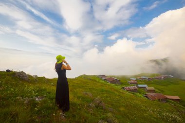 Türkiye'nin kuzeydoğusundaki Karadeniz bölgesinin yeşil doğası, karlı dağları ve geleneksel ahşap yayla evleri (yayla evi). Haziran 2019'da Rize'nin Pokut Yaylası'nda manzara çekimi yapıldı.