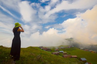 Türkiye'nin kuzeydoğusundaki Karadeniz bölgesinin yeşil doğası, karlı dağları ve geleneksel ahşap yayla evleri (yayla evi). Haziran 2019'da Rize'nin Pokut Yaylası'nda manzara çekimi yapıldı.