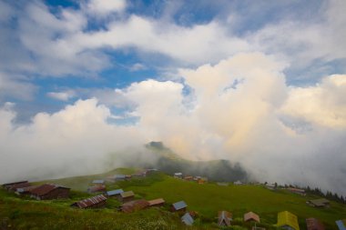 Türkiye'nin kuzeydoğusundaki Karadeniz bölgesinin yeşil doğası, karlı dağları ve geleneksel ahşap yayla evleri (yayla evi). Haziran 2019'da Rize'nin Pokut Yaylası'nda manzara çekimi yapıldı.