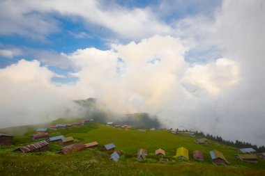 Türkiye'nin kuzeydoğusundaki Karadeniz bölgesinin yeşil doğası, karlı dağları ve geleneksel ahşap yayla evleri (yayla evi). Haziran 2019'da Rize'nin Pokut Yaylası'nda manzara çekimi yapıldı.