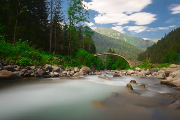 Old historical stone bridge on river under the fog at black sea region of Turkey. Historical Ottoman bridge Taskopru in Senyuva, Cinciva in Armenian, over the Firtina river near Camlihemsin in Rize