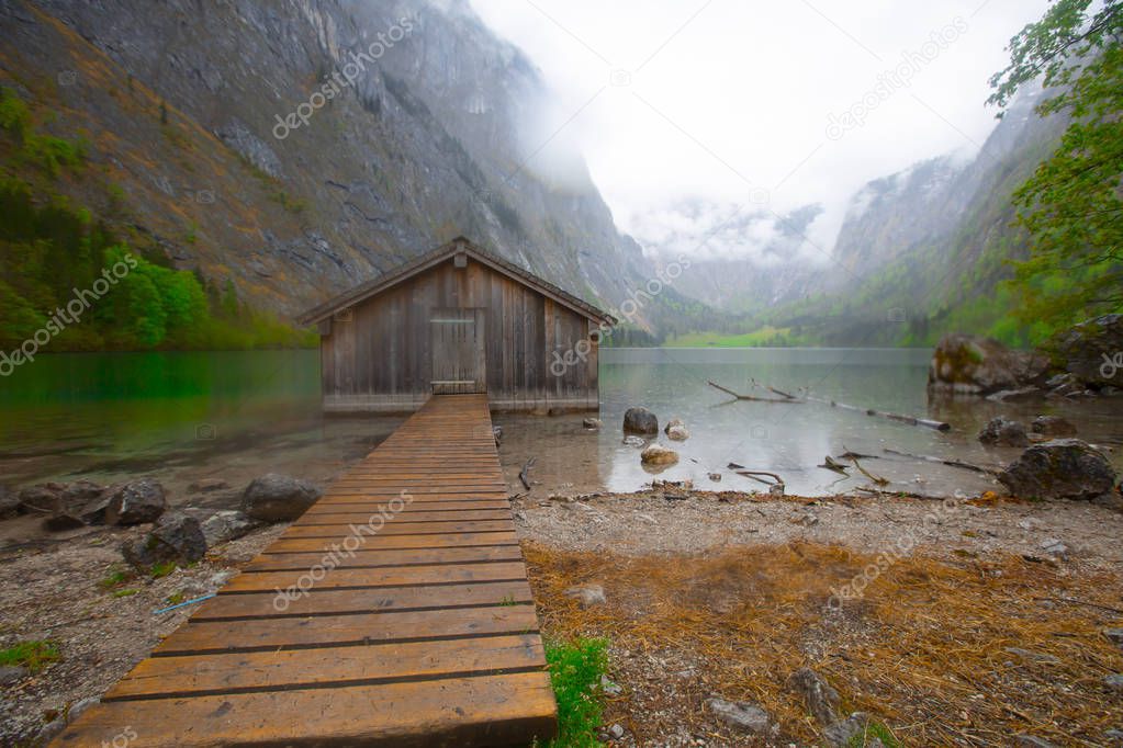 Beautiful view of traditional wooden boat house at the shores of famous Lake Obersee in scenic Nationalpark Berchtesgadener Land on a sunny day in summer, Bavaria, Germany