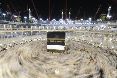Dünyanın dört bir yanından gelen Müslüman hacılar, Suudi Arabistan'da Hac sırasında geceleri Kabe'yi geziyor. Hareket bulanıklığı yakalamak için uzun süre maruz kaldı.