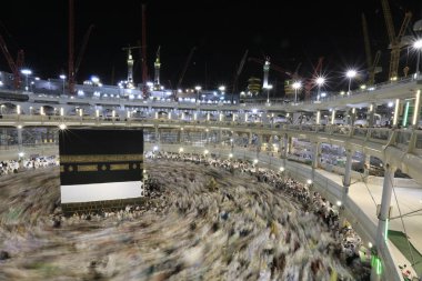 Dünyanın dört bir yanından gelen Müslüman hacılar, Suudi Arabistan'da Hac sırasında geceleri Kabe'yi geziyor. Hareket bulanıklığı yakalamak için uzun süre maruz kaldı.