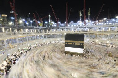 Dünyanın dört bir yanından gelen Müslüman hacılar, Suudi Arabistan'da Hac sırasında geceleri Kabe'yi geziyor. Hareket bulanıklığı yakalamak için uzun süre maruz kaldı.