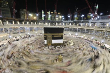 Dünyanın dört bir yanından gelen Müslüman hacılar, Suudi Arabistan'da Hac sırasında geceleri Kabe'yi geziyor. Hareket bulanıklığı yakalamak için uzun süre maruz kaldı.