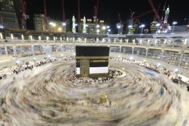 Dünyanın dört bir yanından gelen Müslüman hacılar, Suudi Arabistan'da Hac sırasında geceleri Kabe'yi geziyor. Hareket bulanıklığı yakalamak için uzun süre maruz kaldı.