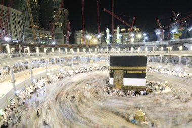 Dünyanın dört bir yanından gelen Müslüman hacılar, Suudi Arabistan'da Hac sırasında geceleri Kabe'yi geziyor. Hareket bulanıklığı yakalamak için uzun süre maruz kaldı.