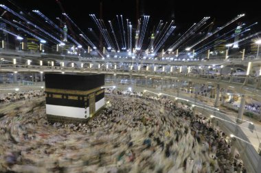 Dünyanın dört bir yanından gelen Müslüman hacılar, Suudi Arabistan'da Hac sırasında geceleri Kabe'yi geziyor. Hareket bulanıklığı yakalamak için uzun süre maruz kaldı.