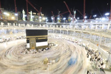 Dünyanın dört bir yanından gelen Müslüman hacılar, Suudi Arabistan'da Hac sırasında geceleri Kabe'yi geziyor. Hareket bulanıklığı yakalamak için uzun süre maruz kaldı.
