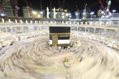Dünyanın dört bir yanından gelen Müslüman hacılar, Suudi Arabistan'da Hac sırasında geceleri Kabe'yi geziyor. Hareket bulanıklığı yakalamak için uzun süre maruz kaldı.