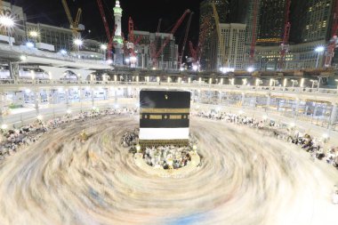 Dünyanın dört bir yanından gelen Müslüman hacılar, Suudi Arabistan'da Hac sırasında geceleri Kabe'yi geziyor. Hareket bulanıklığı yakalamak için uzun süre maruz kaldı.