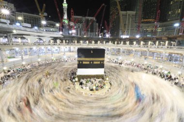 Dünyanın dört bir yanından gelen Müslüman hacılar, Suudi Arabistan'da Hac sırasında geceleri Kabe'yi geziyor. Hareket bulanıklığı yakalamak için uzun süre maruz kaldı.