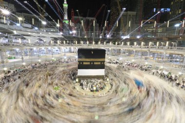 Dünyanın dört bir yanından gelen Müslüman hacılar, Suudi Arabistan'da Hac sırasında geceleri Kabe'yi geziyor. Hareket bulanıklığı yakalamak için uzun süre maruz kaldı.