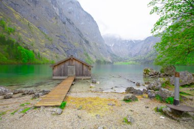 Yaz aylarında mavi gökyüzü ve bulutlar ile güzel bir güneşli bir günde doğal Obersee Gölü'nde geleneksel eski ahşap tekne evi Pastoral görünümü, Millipark Berchtesgadener Land, Bavyera, Almanya