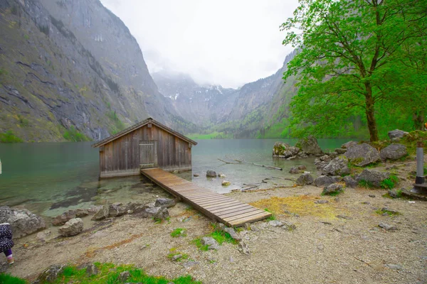 Yaz aylarında mavi gökyüzü ve bulutlar ile güzel bir güneşli bir günde doğal Obersee Gölü'nde geleneksel eski ahşap tekne evi Pastoral görünümü, Millipark Berchtesgadener Land, Bavyera, Almanya