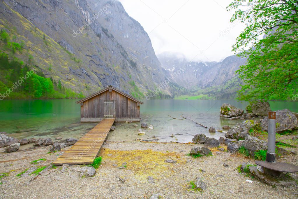 Idyllic view of traditional old wooden boat house at scenic Lake Obersee on a beautiful sunny day with blue sky and clouds in summer, Nationalpark Berchtesgadener Land, Bavaria, Germany