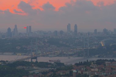 Güneş doğarken İstanbul Boğaz Köprüsü 'nün fotoğrafı. Asya ve Avrupa olmak üzere iki farklı kıtayı birleştirir. Burada görünen kıta Asya 'dır. Koyu mavi gökyüzü ve detaylı binalar görünür.. 
