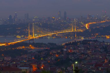 Güneş doğarken İstanbul Boğaz Köprüsü 'nün fotoğrafı. Asya ve Avrupa olmak üzere iki farklı kıtayı birleştirir. Burada görünen kıta Asya 'dır. Koyu mavi gökyüzü ve detaylı binalar görünür.. 