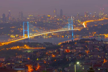 Güneş doğarken İstanbul Boğaz Köprüsü 'nün fotoğrafı. Asya ve Avrupa olmak üzere iki farklı kıtayı birleştirir. Burada görünen kıta Asya 'dır. Koyu mavi gökyüzü ve detaylı binalar görünür.. 