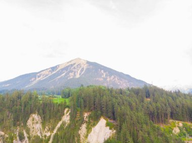 İsviçre Alpleri 'ndeki eğri bir raydaki taş bir köprüden geçen kırmızı dar gösterge..