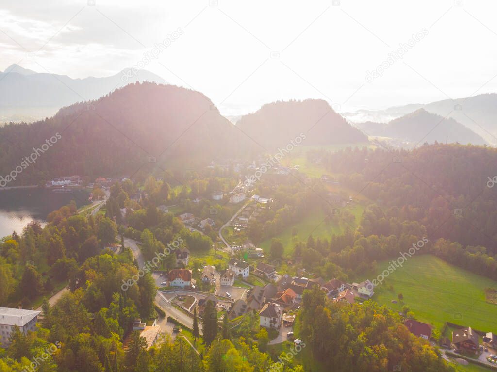 Aerial view of the colorful forest and Lake Bled with a small island with a church. Sunrise in Slovenia in the fall