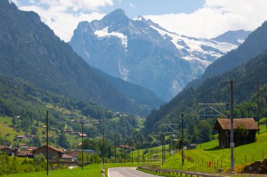 Şaşırtıcı İsviçre dağlık arazisi, yeşil tarlalarda ahşap kiremitler ve arka planda karlı zirveler bulunan yüksek dağlar, Grindelwald, Bernese Oberland, İsviçre, Avrupa