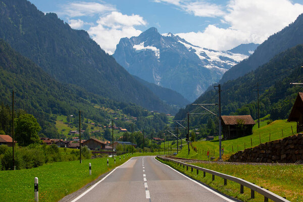 Amazing Swiss alpine mountain landscape, wooden chalets on green fields and high mountains with snowy peaks in background, Grindelwald, Bernese Oberland, Switzerland, Europe