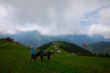 Türkiye 'nin Pokut Masa Diyarı bölgesindeki tepedeki kır evleri mavi gökyüzü ve bulutlu.