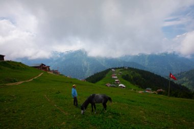 Türkiye 'nin Pokut Masa Diyarı bölgesindeki tepedeki kır evleri mavi gökyüzü ve bulutlu.