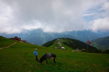 Türkiye 'nin Pokut Masa Diyarı bölgesindeki tepedeki kır evleri mavi gökyüzü ve bulutlu.