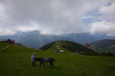 Türkiye 'nin Pokut Masa Diyarı bölgesindeki tepedeki kır evleri mavi gökyüzü ve bulutlu.