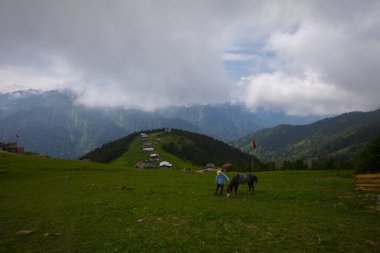 Türkiye 'nin Pokut Masa Diyarı bölgesindeki tepedeki kır evleri mavi gökyüzü ve bulutlu.