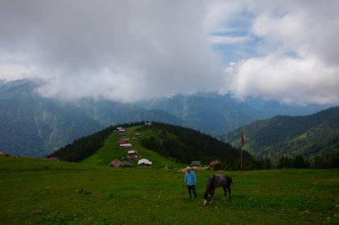 Türkiye 'nin Pokut Masa Diyarı bölgesindeki tepedeki kır evleri mavi gökyüzü ve bulutlu.