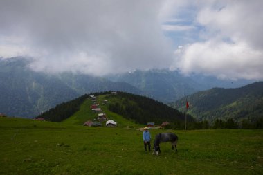 Türkiye 'nin Pokut Masa Diyarı bölgesindeki tepedeki kır evleri mavi gökyüzü ve bulutlu.