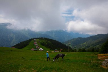Türkiye 'nin Pokut Masa Diyarı bölgesindeki tepedeki kır evleri mavi gökyüzü ve bulutlu.