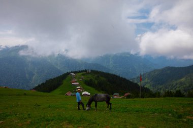 Türkiye 'nin Pokut Masa Diyarı bölgesindeki tepedeki kır evleri mavi gökyüzü ve bulutlu.