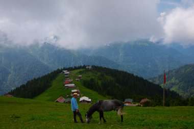 Türkiye 'nin Pokut Masa Diyarı bölgesindeki tepedeki kır evleri mavi gökyüzü ve bulutlu.