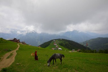 Türkiye 'nin Pokut Masa Diyarı bölgesindeki tepedeki kır evleri mavi gökyüzü ve bulutlu.